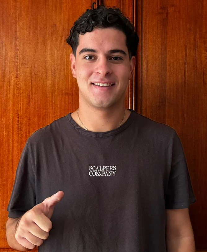 Fotografía de Vicente Lozano, ,exalumno y puntaje nacional PAES, sonriendo y haciendo el gesto de pulgar hacia arriba.